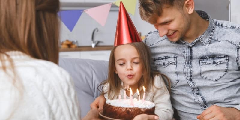 family with kid blowing out candles
