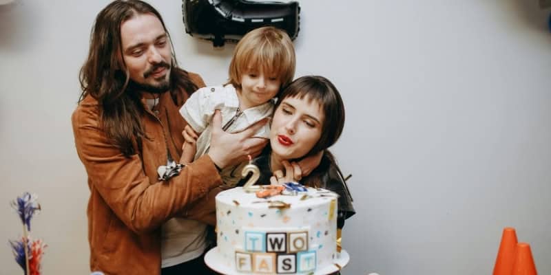 family with kid blowing a #2 candle